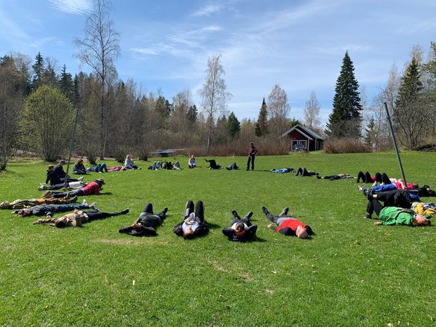 Ihmisiä makaamassa nurmikolla ympyrässä 